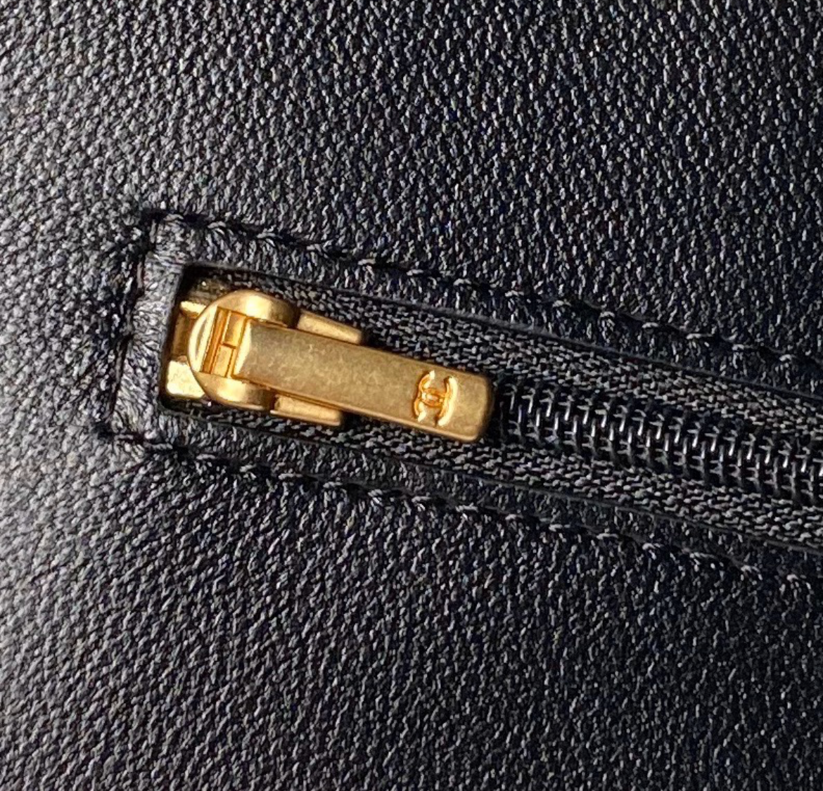 Close-up of a black leather bag with a gold zipper.