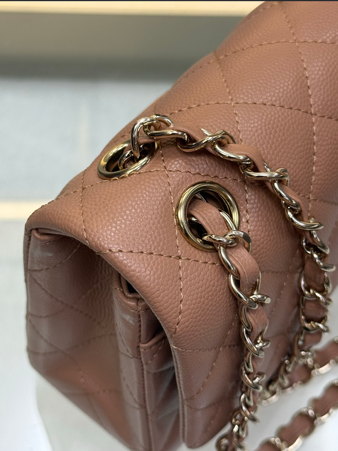 Close-up of a brown quilted handbag with a gold chain strap.